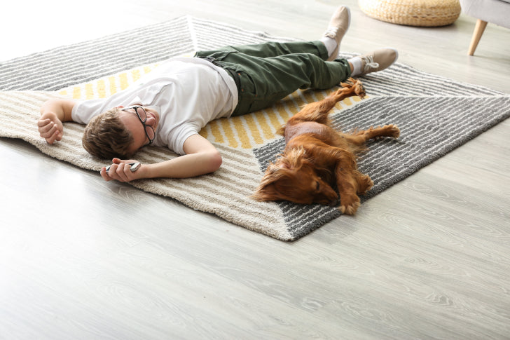 Ein Mann und ein Hund liegen zufrieden auf dem Teppich da alle Gerüche neutralisiert wurden